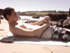 Young guy is lying on the beach and wanking dick
